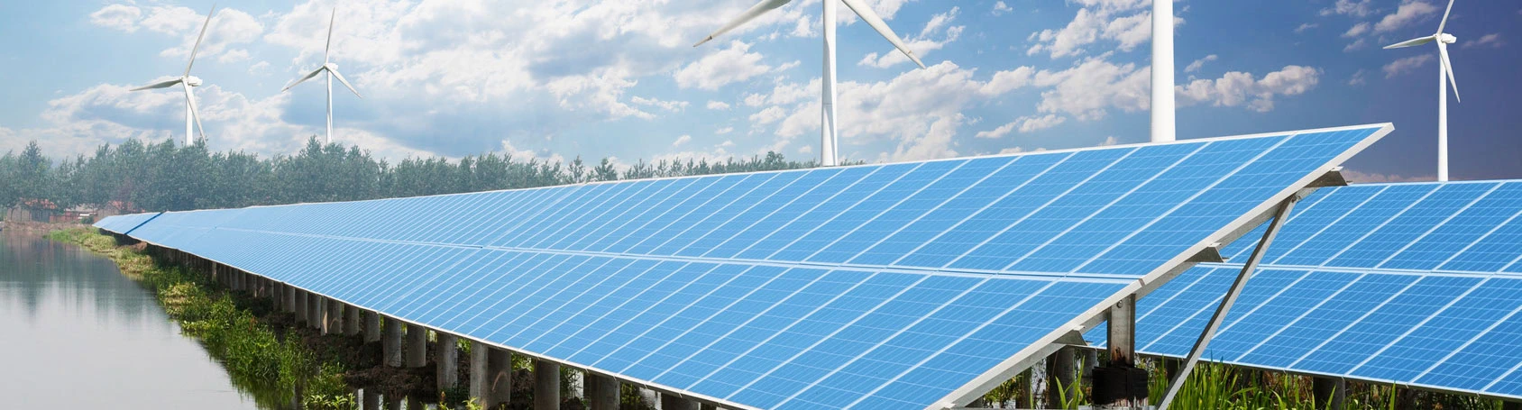 Solar panels are installed on raised platforms over a body of water, with wind turbines in the background under a partly cloudy sky.