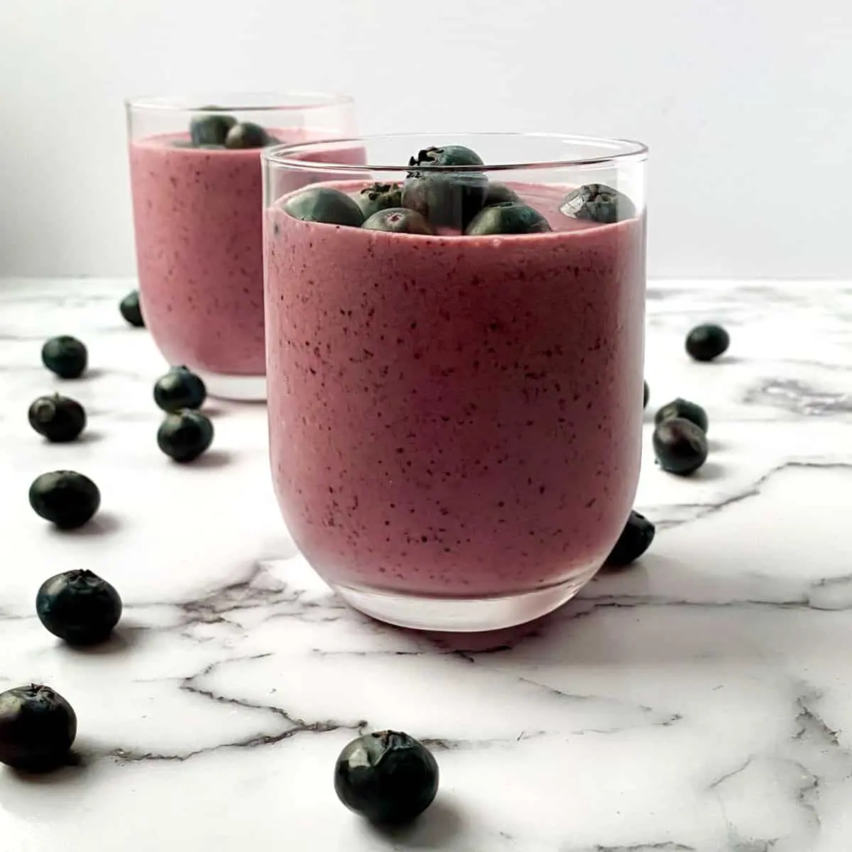 03e30b37-748f-474f-a64f-a9e4c0706520 Blueberry smoothies in clear glasses.