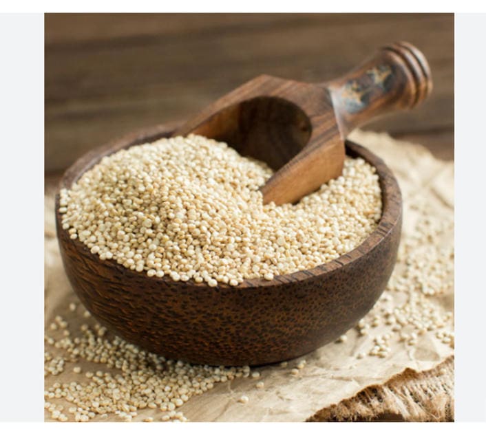Bowl of uncooked quinoa with wooden scoop